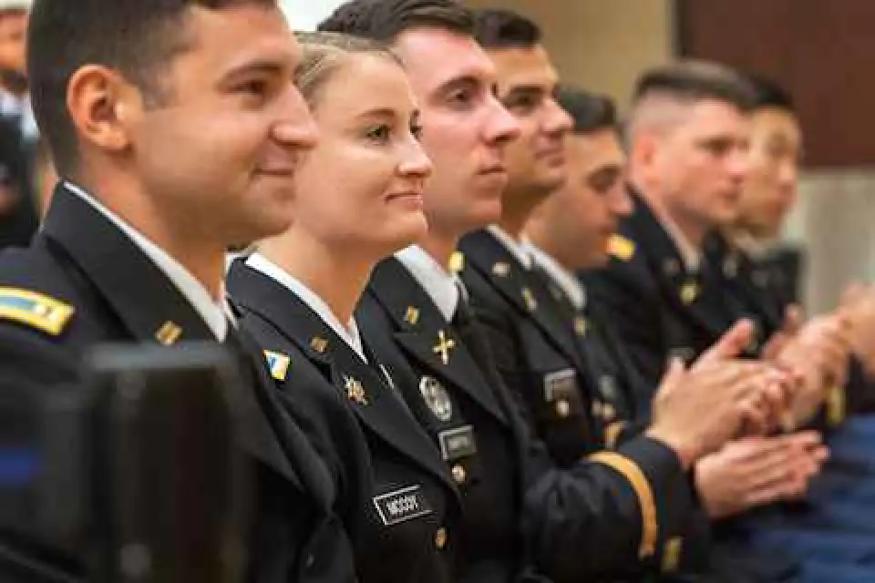 Smiling graduates clap at their commissioning ceremony