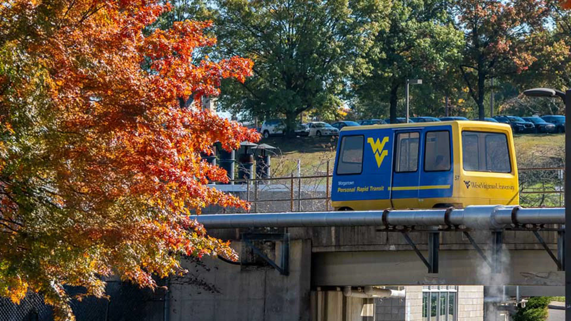 PRT car passing by orange autumn leaves.
